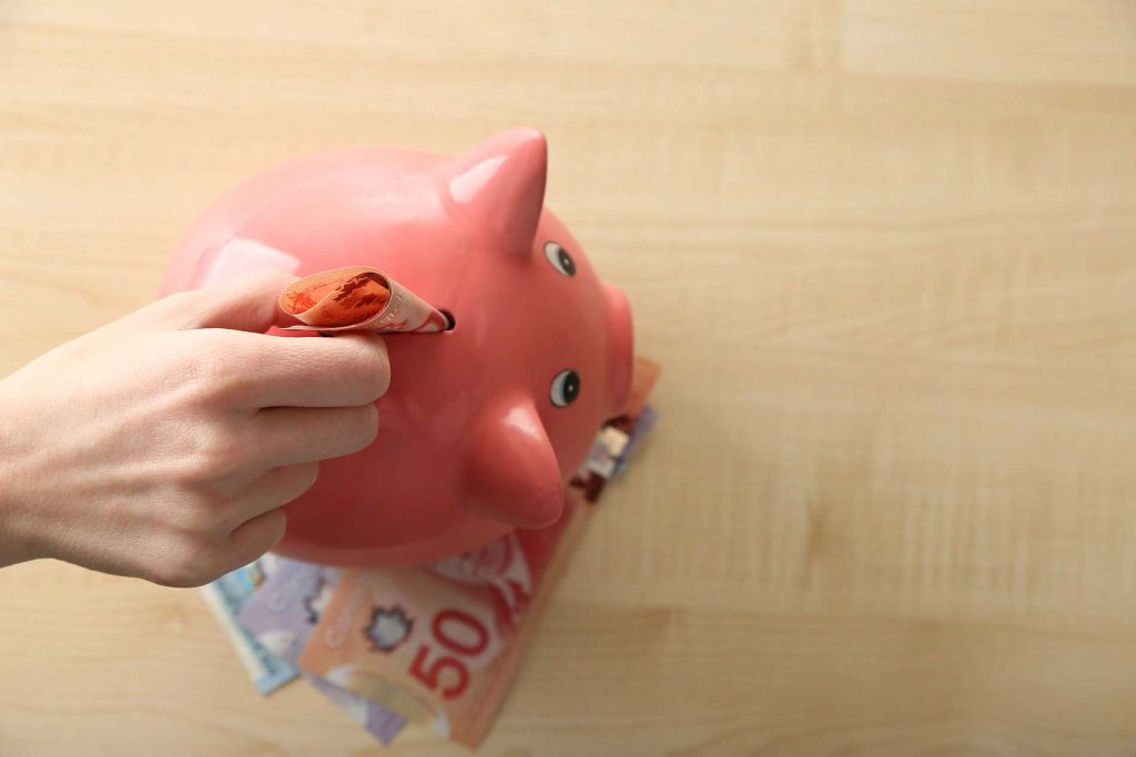 person putting money into a piggy bank